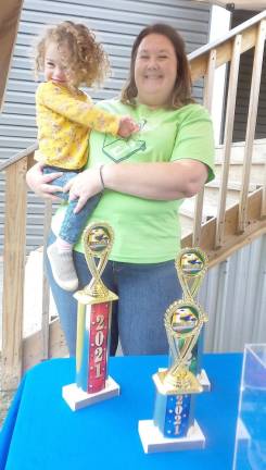 Bridget Fagerholt with daughter Lillian, who is one of 100 in the U.S. with the genetic disorder Tbc1d24. Trophies await the winners of the cornhole tournament. (Photo by Frances Ruth Harris)