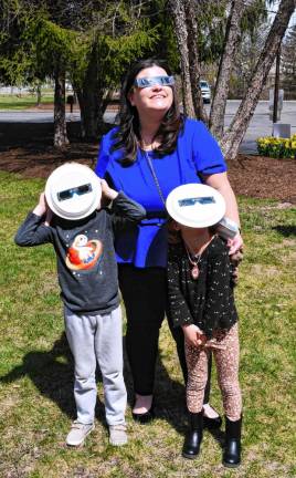 Using safety glasses, Noreen Bredhold of Sussex looks at the eclipse with her children Evan and Grace on Monday, April 8 outside the Dorothy Henry library branch in Vernon. (Photo by Maria Kovic)