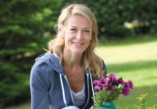 Cheerful blond woman planting flowers in garden
