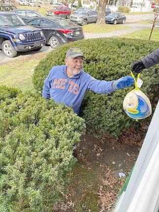 As chief of the “turkey brigade”, volunteer Wilo Bonilla accepts a turkey to give to a waiting client.