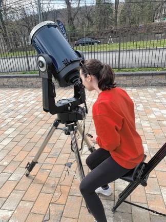 Mary Porebski looks at the solar eclipse through a telescope in front of Vault Liquors in the Bearfort Shopping Village in West Milford. (Photo provided)