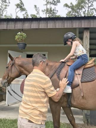 Peter Rizzo adjusts the stirrups for his granddaughter.