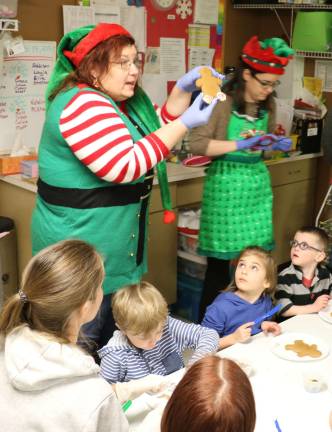 Elf-dieticians help children at CDD decorate gingerbread cookies Sous Chef Allison Wharton (left) tells the children that M&M's make great gingerbread man buttons (Photo provided)