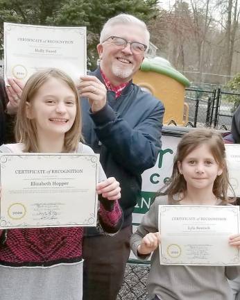 Elizabeth Hopper, county commissioner Matt Osterberg, and Lyla Sustak show off awards