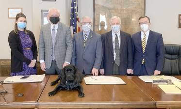 Violet, the Labrador retriever in training to become a comfort dog at Dickson House, gets to hang out on the desk with the Pike County clerk, commissioners, and district attorney (Photo provided)