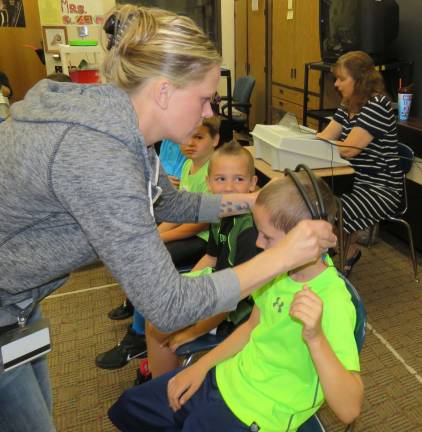 Can you hear me now? Mrs. Nan Croll (seated with testing machine) and Mrs. Heather Mulligan (PTA mom) prepare Nicholas Jorgenson for his turn at completing his hearing test.