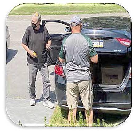 Volunteer Verne Kreger (back to camera) loads groceries into client’s car (Photo provided)