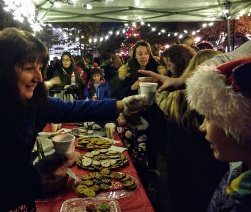 Santa arrives, the tree lights up, and all is well in Milford Volunteers serve cookies and hot drinks at the stand during the tree-lighting ceremony (Photo by Anya Tikka)