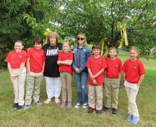 DVE-TV student-reporters attend 9/11 memorial service With yellow ribbons, from left: Ava McAveney, Sydney Garrison, Flo Santini, Katharine Quinn, Tillie Geidel Conklin (daughter of Gary Geidel), Samuel Yost, Ben Bailor, and Kaylee Kurcon (Photo provided)