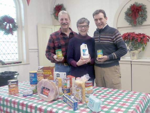 Jim and Pat Snodgrass (left) stand with Bruce Baker, volunteers for the Ecumenical Food Pantry of Pike County, in front of a display of food for Christmas.