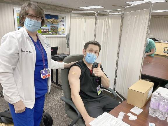 Nicholas Marano, respiratory therapist, gives a thumbs up after being vaccinated by Janice Pettinato, RN, at Wayne Memorial Hospital.