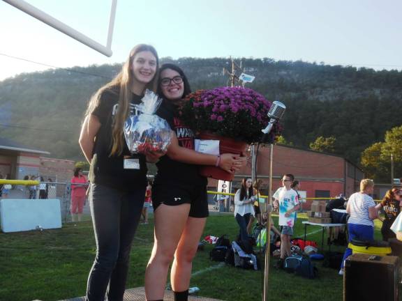 That Warrior spirit Karley May and Meghan Kiedlrer, both 17 and in 12th grade, manned the girls volleyball raffle. They're holding some of the awards for winners, flowers from Meyers and a basket from Fochman Cafe in Dingman (Photo by Melissa McMonagle)