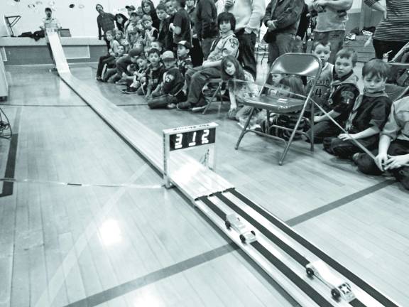 Race Time at the Pinewood Derby Guests watch as cars wiz by.