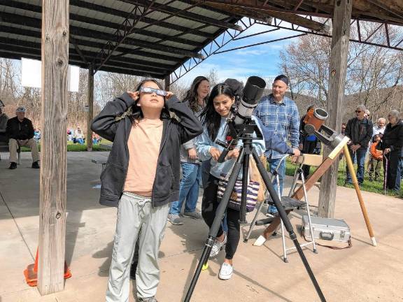 Noah Tymczyszyn, 10, of Warwick, N.Y., looks at the partial solar eclipse through safety glasses as his mother, Cat, uses a telescope set up at the Wallkill River National Wildlife Refuge in Sussex. (Photo by Kathy Shwiff)