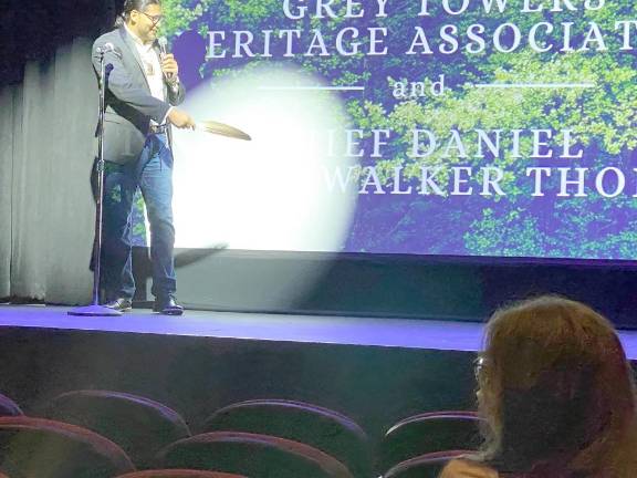 Thomas pointing with an eagle Feather to screen showing title of film