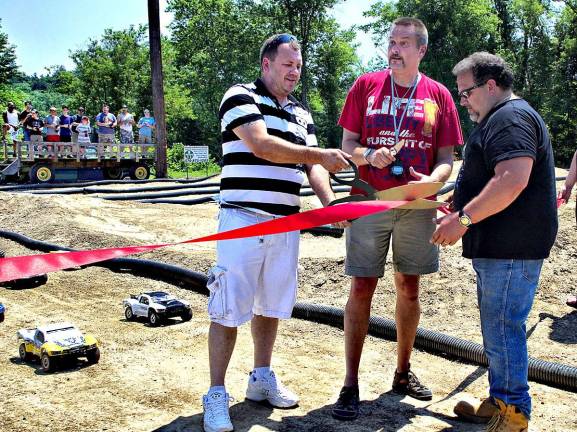 A ribbon cutting ceremony opened the new park. From the left: George Featherman, Chris Graham and John Fernandez did the honors as car &quot;drivers&quot; in the background waited for the checkered flag.
