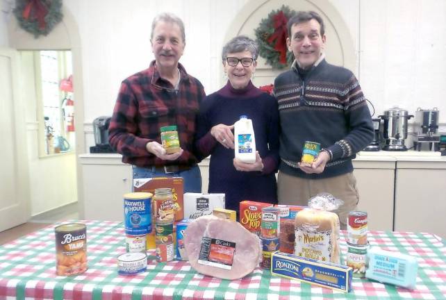 Food pantry volunteers Jim and Pat Snodgrass (left) and Bruce Baker with groceries that will help feed those in need at Christmas. Each family may chose between a turkey or a ham. The food pantry has found that the need for food has steadily increased over the past year.