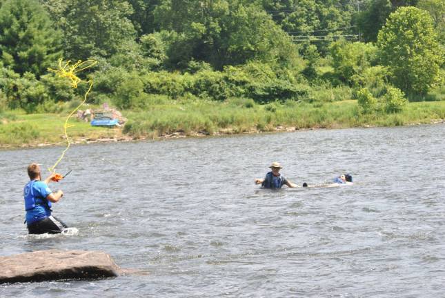 Keeping the Delaware River clean Kittatinny Canoes River Guide Alan 'Hoss' Stevens throws a rope to Nisha Zutshi who's being helped by the group's Bob Jackson after her kayak turned over in the rapids in Barryville. She was fine after the rescue and continued her paddle.