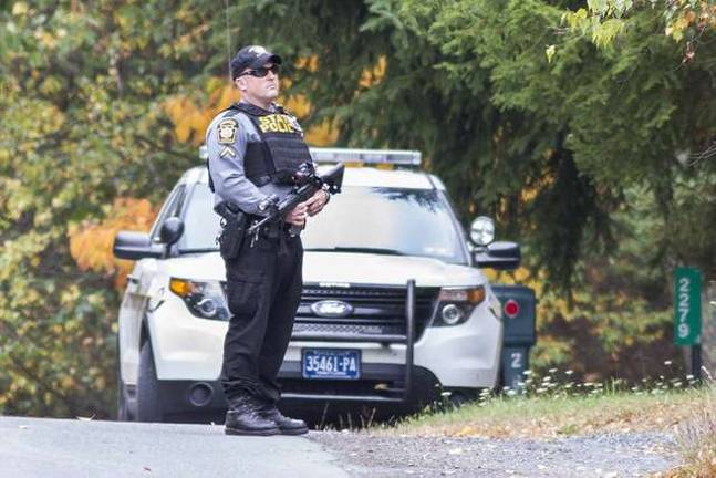 Man hunt continues A Pennsylvania State Police Officer carrying a shotgun.