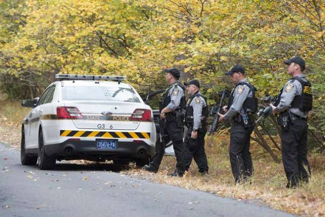 Man hunt continues Heavily armed Pennsylvania State Police standby at the side of a roadway in the Eric Frein search area while a state police helicopter flies overhead on the 21st day of the fugitive manhunt Friday, Oct. 3.