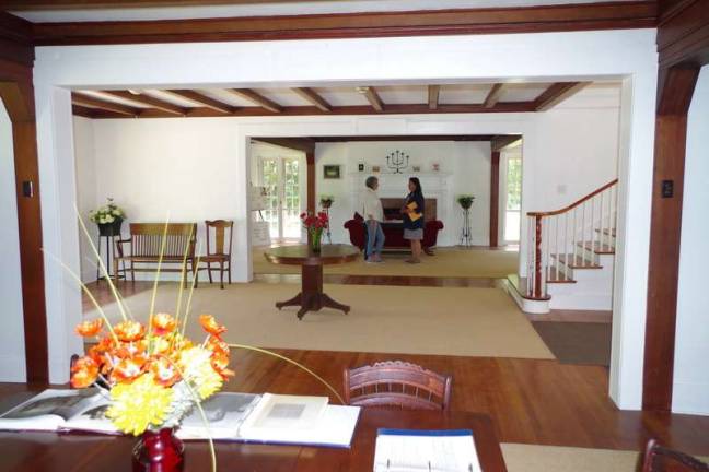 Seen from the dining room, two guests talk in the living room of the main house. The stairs to the right lead from the foyer to the second-floor bedrooms. (Photo by George Leroy Hunter)