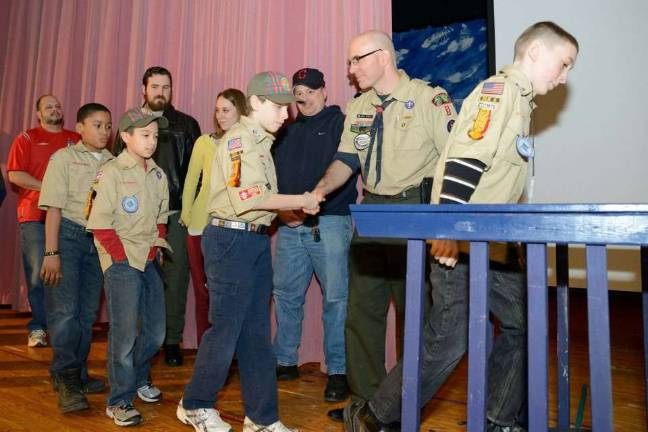 Cub Scouts graduate to Boy Scouts Photo courtesy: Douglas Crane Cubmaster John Bedell congratulates each of his six Webelos Scouts as the walk over the bridge and transition from Cub Scouts to Boys Scouts at the annual Blue and Gold Banquet.