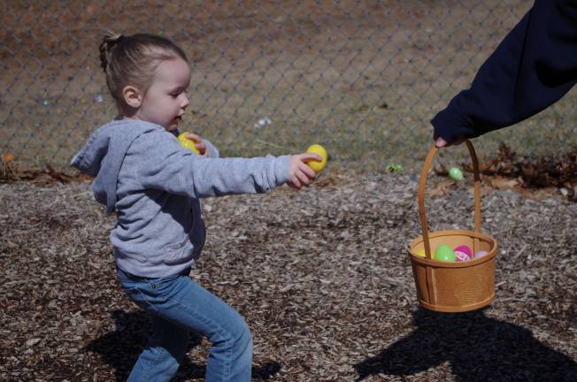 Easter egg hunt Three year old Kira Sanders of Dingmans Ferry carries an arm load of Easter eggs to a waiting basket.