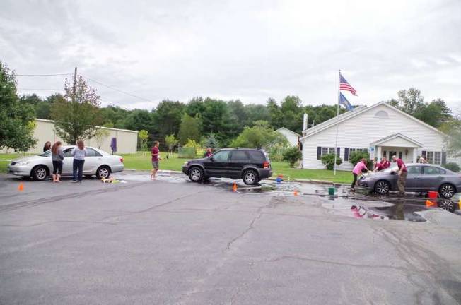 The crew is busy washing a line of cars.