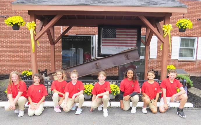 From left to right are: Madilyn Latini, Adelyn Gamer, Maeve Kaiser, Gia Cosentino, Hazel Pope, Chanel Schock, Dom DeLauro and Luca Slain. The piece of iron behind the students came from the debris of the Twin Towers.