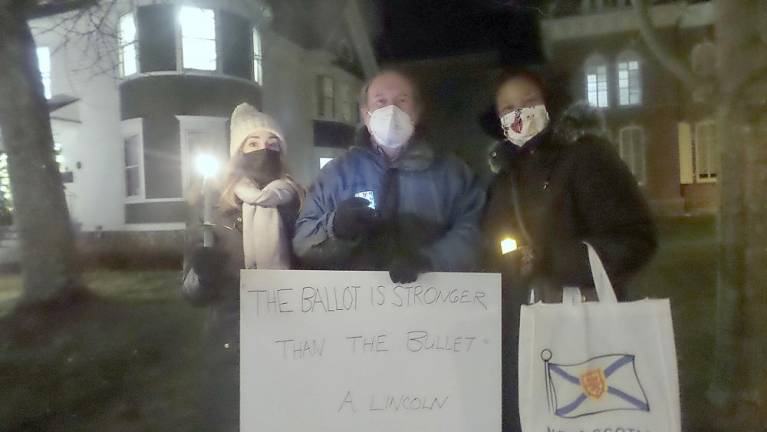 Meg Rosenfeld, Ed Gragret and Cheryl Glenn stood with candles and a message from President Lincoln, The ballot is stronger than the bullet. (Photo by Frances Ruth Harris)