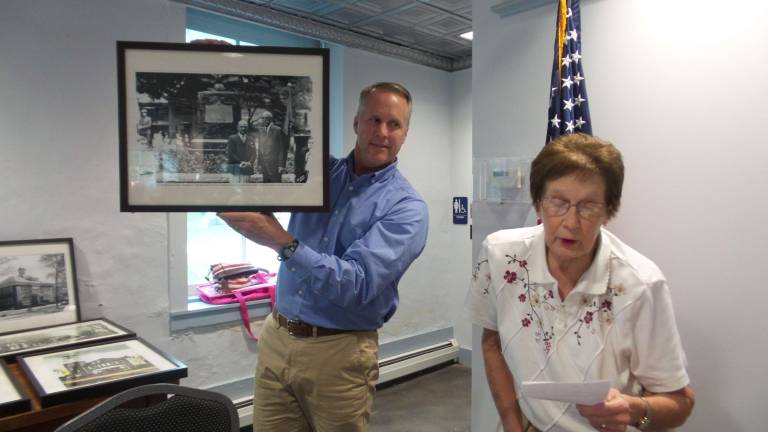 Skip Gregory's historic photos to grace meeting hall Milford Borough President Patrick Beck holds up a photograph as Lorraine Gregory makes her presentation (Photo by Frances Ruth Harris)