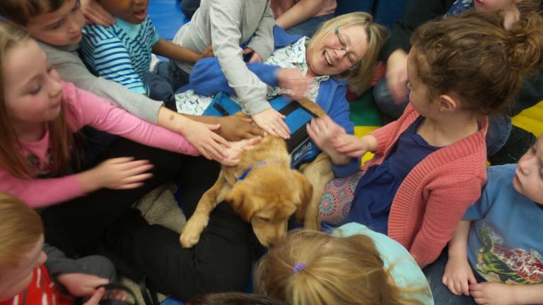 Benni and his trainer, Chrisanne Cubby, are at the center of a group petting extravaganza at Kids Play Today (Photo by Frances Ruth Harris)