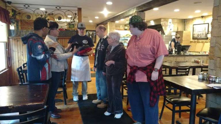 Devereaux visitors learn pizza business from a pro Pizzeria owner Colin Smith distributes T-shirts to the happy visitors after their meal (Photo by Anya Tikka)