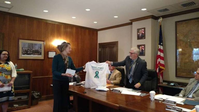 Commissioners raise awareness about scourge of domestic violence Tamara Chant, executive director of Safe Haven, presents Commisioners' Chair Matt Osterberg with a T-shirt after receiving a $10,000 check from the commissioners in support of the organization (Photo by Anya Tikka)
