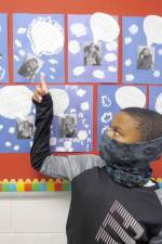 Student Rayvon Carr, who came up with the idea, points to Ms. Paz’s bulletin board. (Photo by Peg Snure)