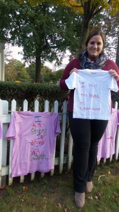 Safe Haven's Chelsea Falotice with some of the tees lining the fence of Milford's Community House. (Photo by Frances Ruth Harris)