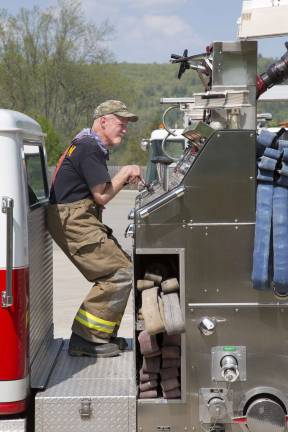 A firefighter from the Deerpark Fire District operates a lever on the pump panel while fighting the townhouse fire in Matamoras (Photo by Robert Breese)