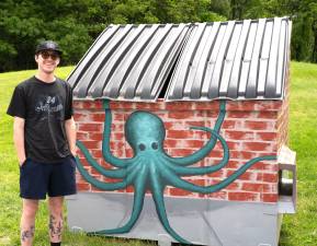Artist Dempsey Langan, who graduated from ESU’s integrated Art + Design program, near the design he created for the dumpster outside the Goat on Main restaurant.