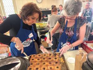 Volunteers Phyllis Fernandez (left) and Rebecca Masters (right) prepare food for the community lunch.