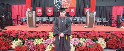 Alex Walsh stands in front of the stage of graduation day.