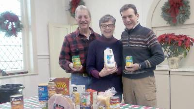 Jim and Pat Snodgrass (left) stand with Bruce Baker, volunteers for the Ecumenical Food Pantry of Pike County, in front of a display of food for Christmas.