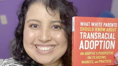 Melissa Guida-Richards is shown with her new book, “What White Parents Should Know About Transracial Adoption”.