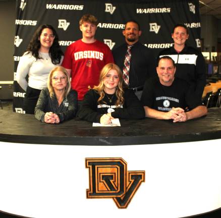 Kate Prior signs her letter of intent to wrestle at Ursinus College. Front row (L-R): Becky Prior, Kate Prior, and Thomas Prior. Back row (L-R): Assistant coach Karley May, brother Tom Prior, head coach Evan Bates, and coach Adalyn Ross.