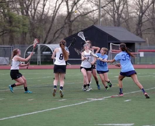 The ball rises above battling lacrosse players