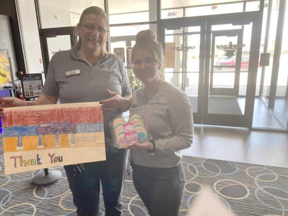 Roxanne DeLellas, General Manager at Flagship holding the thank you card the students made, with Liz Ronda, Assistant manager