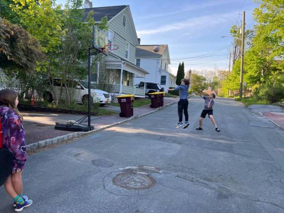 Liam Natale and Matthew Peacock playing basketball on John Street. After a neighbor’s complaint, they have been warned that playing in the street. is “contrary to local law.”