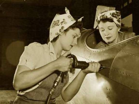 A worker drives rivets into a World War II aircraft while her co-worker sits in the cockpit (Photo: NWHP)