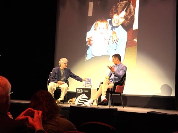 Bob Eckstein talking with Michael Kosta. Behind them is a photo Kosta as a baby with his mother who taught him to play tennis.