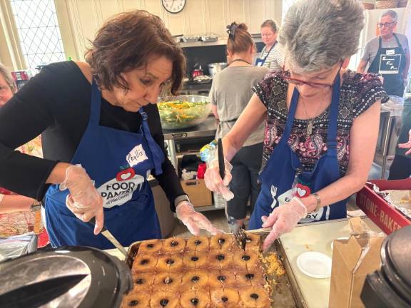 Volunteers Phyllis Fernandez (left) and Rebecca Masters (right) prepare food for the community lunch.