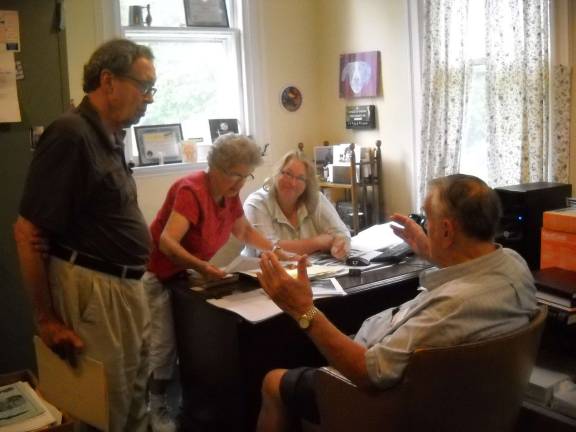 At desk seated is Lori Strelecki, standing Centa Quinn, seated in front of desk Skip Gregory, standing George Fluhr.